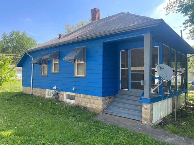 244 N 7th Ave, Kankakee, IL 60901 - view of property exterior featuring a chimney, a sunroom, a lawn, entry steps, and a shingled roof