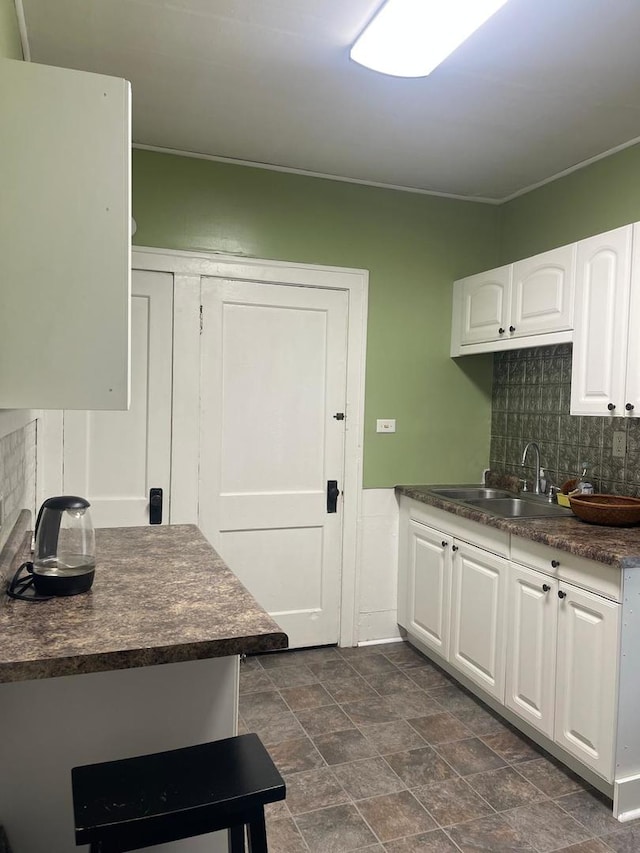 244 N 7th Ave, Kankakee, IL 60901 - kitchen featuring dark countertops, a sink, white cabinets, tasteful backsplash, and stone finish floors