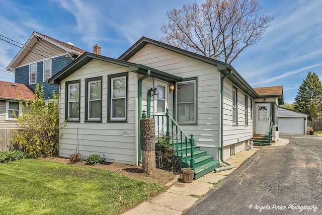 view of front of property featuring entry steps, a detached garage, an outbuilding, and a front yard