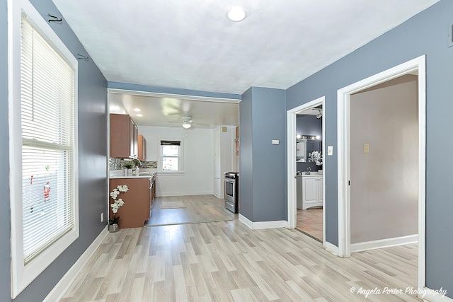 hall with light wood-type flooring, baseboards, and a sink