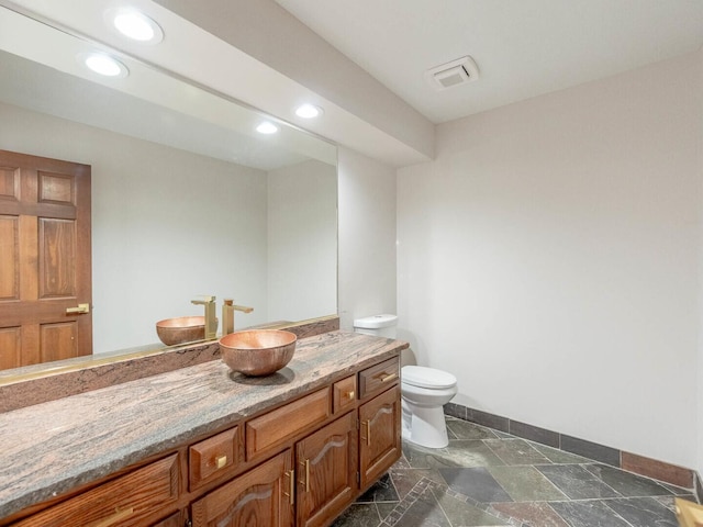 bathroom with toilet, recessed lighting, baseboards, vanity, and stone finish floors