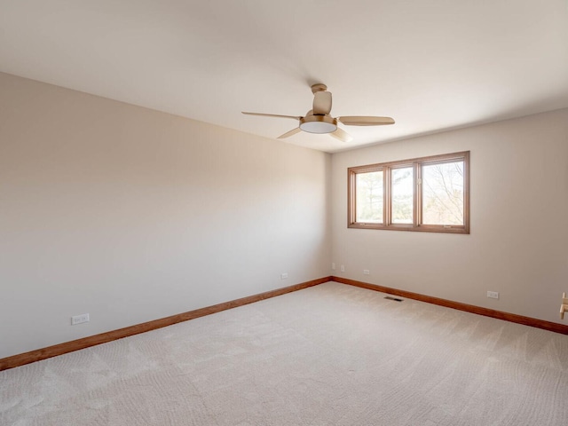 spare room featuring ceiling fan, baseboards, and light carpet