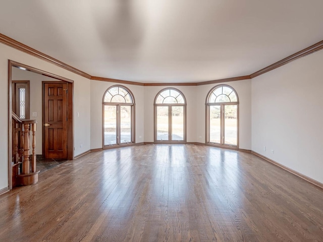 unfurnished living room with wood finished floors, crown molding, and baseboards