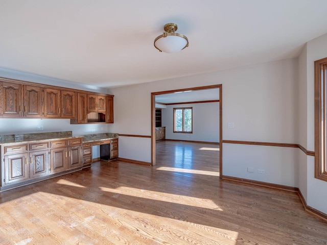 kitchen with wood finished floors, baseboards, and brown cabinets