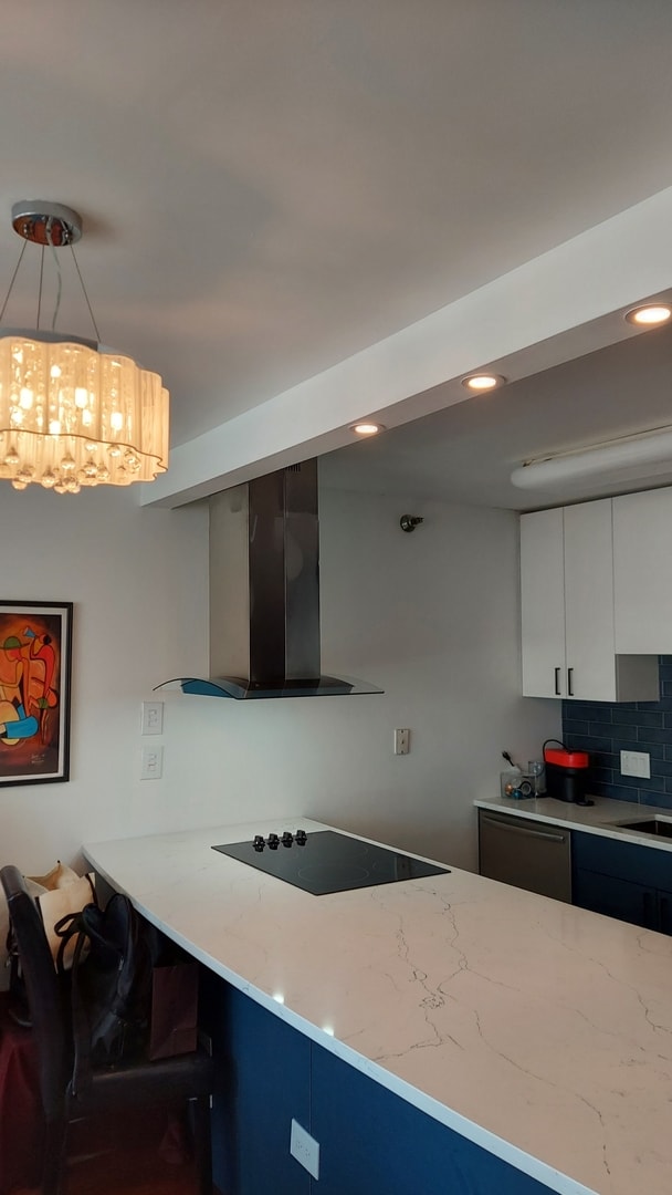 345 N La Salle Dr Unit 3305, Chicago, IL 60654 - kitchen featuring wall chimney exhaust hood, black electric cooktop, light stone counters, white cabinetry, and tasteful backsplash