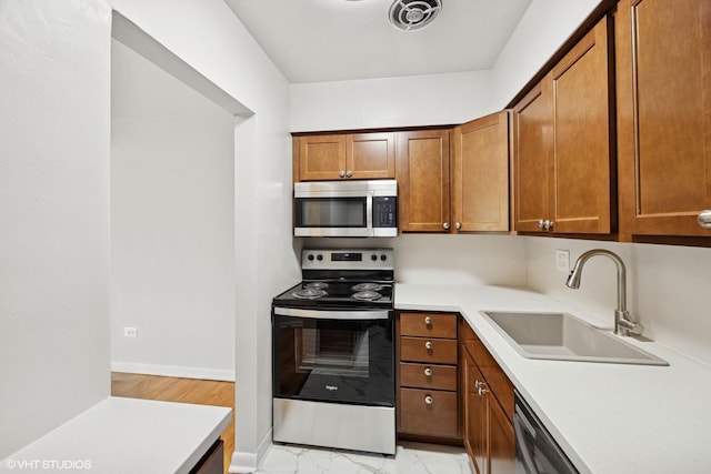 405 Wesley Ave Unit 6, Oak Park, IL 60302 - kitchen featuring stainless steel appliances, a sink, light countertops, brown cabinets, and light marble finish flooring