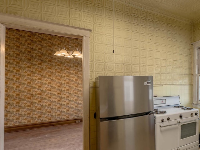 4028 W Roscoe St, Chicago, IL 60641 - kitchen with freestanding refrigerator, range with two ovens, wallpapered walls, wood finished floors, and baseboards