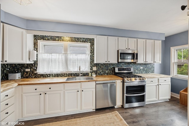 432 Selborne Rd, Riverside, IL 60546 - kitchen with butcher block countertops, stainless steel appliances, a sink, wood finished floors, and white cabinetry