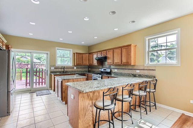 15157 Hilltop Ct, Orland Park, IL 60462 - kitchen with appliances with stainless steel finishes, exhaust hood, a peninsula, a kitchen island, and a kitchen bar