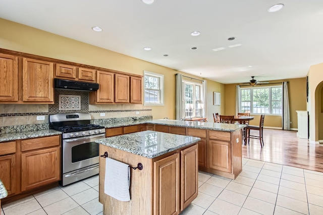 15157 Hilltop Ct, Orland Park, IL 60462 - kitchen featuring gas stove, under cabinet range hood, a kitchen island, brown cabinets, and light tile patterned flooring