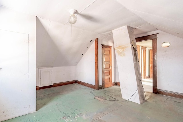 additional living space with lofted ceiling, concrete floors, and baseboards