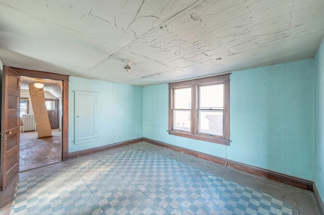 unfurnished room with healthy amount of natural light and radiator