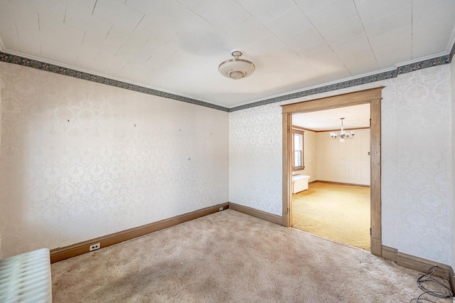 carpeted empty room with a chandelier, baseboards, crown molding, and wallpapered walls