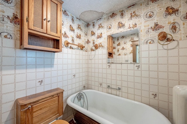 bathroom featuring a freestanding bath, tile walls, a textured ceiling, and radiator