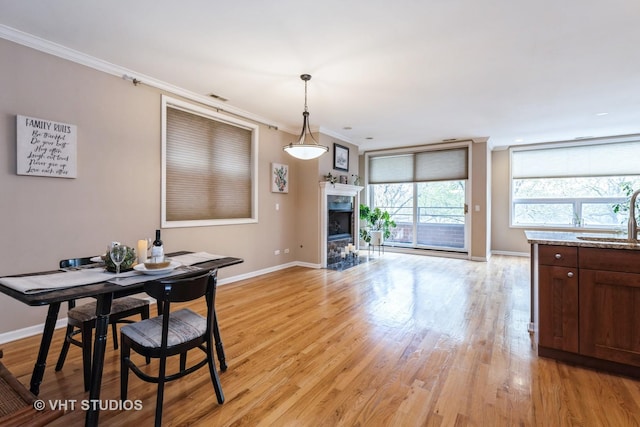 934 W Cuyler Ave Unit 2D, Chicago, IL 60613 - dining area featuring baseboards, crown molding, light wood-type flooring, and a fireplace with flush hearth