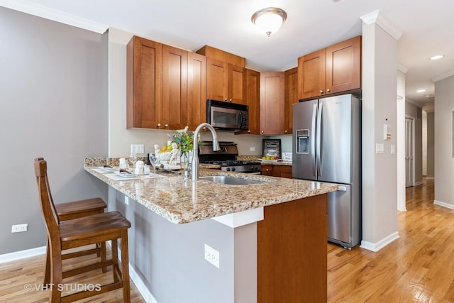934 W Cuyler Ave Unit 2D, Chicago, IL 60613 - kitchen featuring appliances with stainless steel finishes, a peninsula, light wood-type flooring, a breakfast bar area, and baseboards