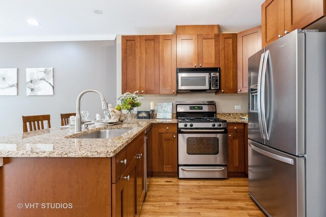 934 W Cuyler Ave Unit 2D, Chicago, IL 60613 - kitchen with stainless steel appliances, a sink, light wood-type flooring, brown cabinetry, and a peninsula