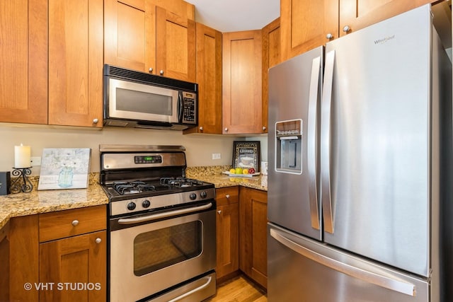 934 W Cuyler Ave Unit 2D, Chicago, IL 60613 - kitchen featuring appliances with stainless steel finishes, brown cabinets, light stone countertops, and light wood-type flooring