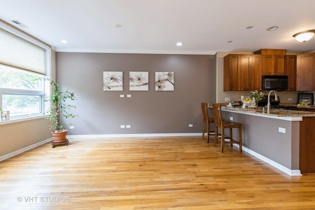 934 W Cuyler Ave Unit 2D, Chicago, IL 60613 - kitchen featuring stainless steel stove, a kitchen bar, light wood finished floors, brown cabinetry, and crown molding