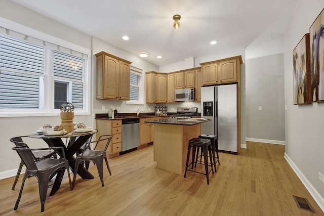 6025 N Ridge Ave Unit 1W, Chicago, IL 60660 - kitchen with stainless steel appliances, a center island, light wood finished floors, a kitchen bar, and dark countertops
