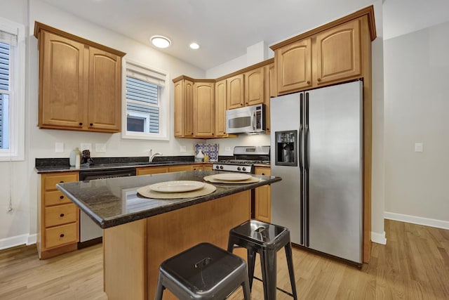 6025 N Ridge Ave Unit 1W, Chicago, IL 60660 - kitchen with stainless steel appliances, light wood-style flooring, a kitchen island, a kitchen breakfast bar, and dark stone countertops