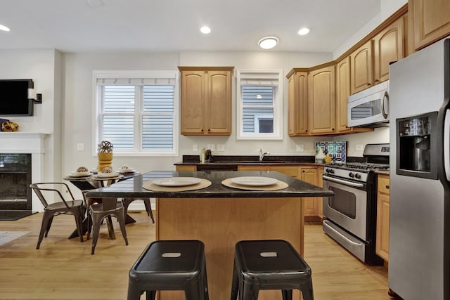 6025 N Ridge Ave Unit 1W, Chicago, IL 60660 - kitchen with appliances with stainless steel finishes, a center island, dark countertops, a kitchen breakfast bar, and light wood finished floors