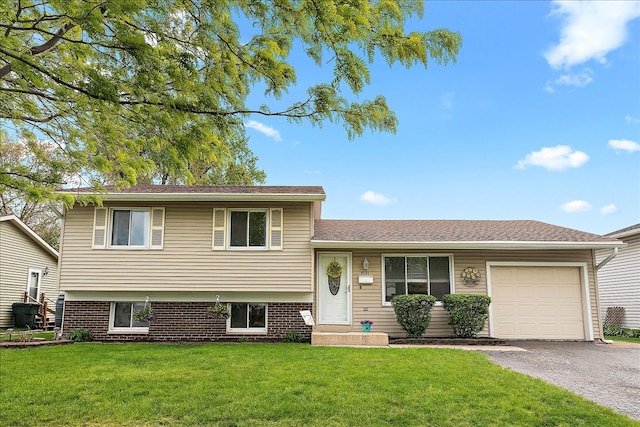 tri-level home featuring an attached garage, a front lawn, driveway, and brick siding