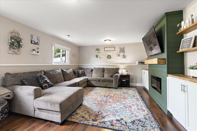 living area with a large fireplace and dark wood finished floors