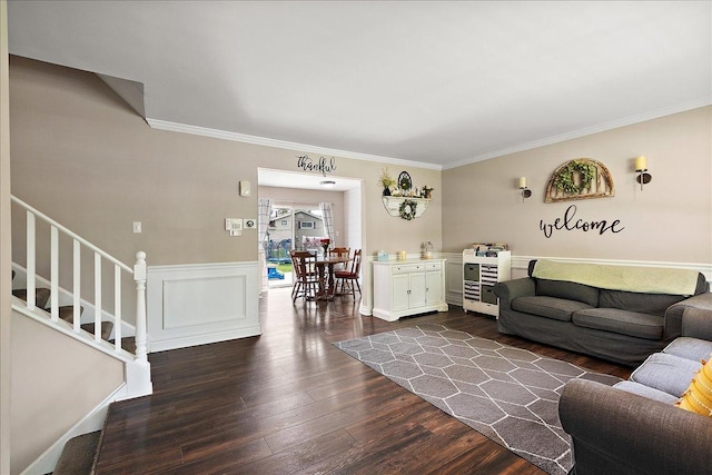 living area featuring stairway, crown molding, dark wood-style floors, and a wainscoted wall