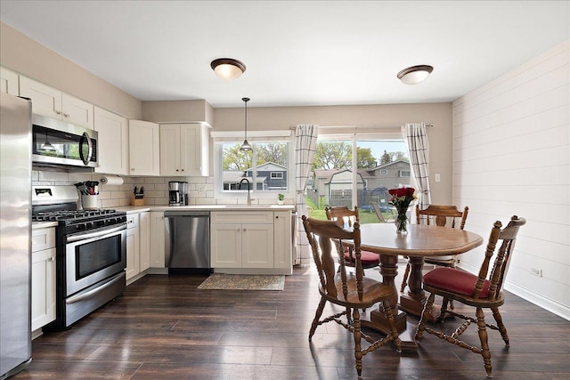 kitchen featuring stainless steel appliances, a sink, light countertops, dark wood-style flooring, and decorative backsplash
