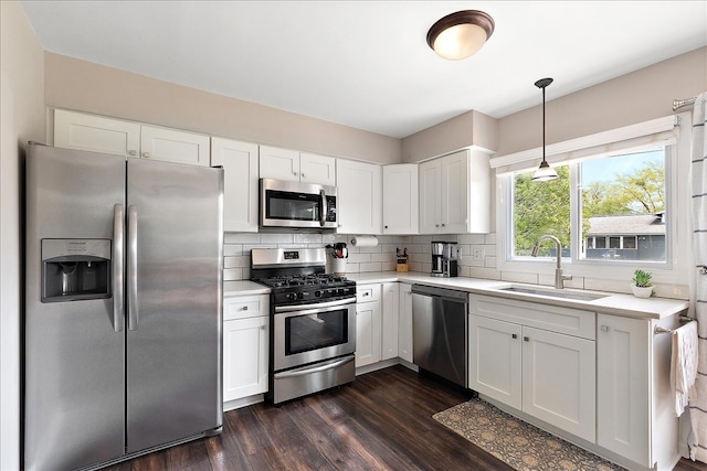 kitchen featuring stainless steel appliances, a sink, light countertops, and dark wood-style flooring