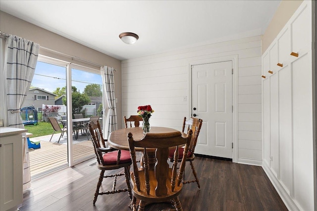 dining room with dark wood finished floors and wooden walls