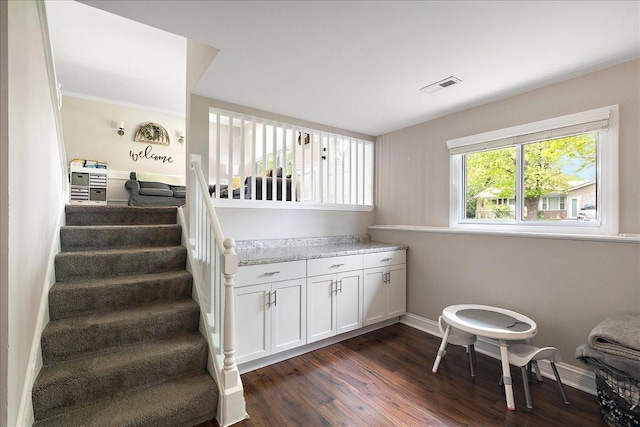 stairway featuring wood finished floors, baseboards, and crown molding