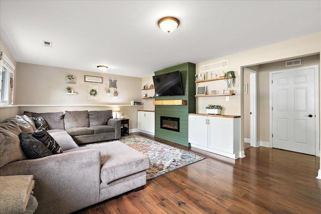 living room featuring dark wood-type flooring, a large fireplace, and baseboards