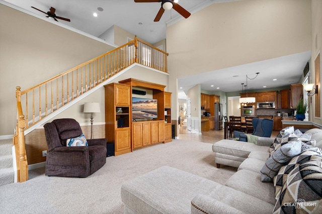 living room featuring a ceiling fan, stairway, light colored carpet, a high ceiling, and recessed lighting