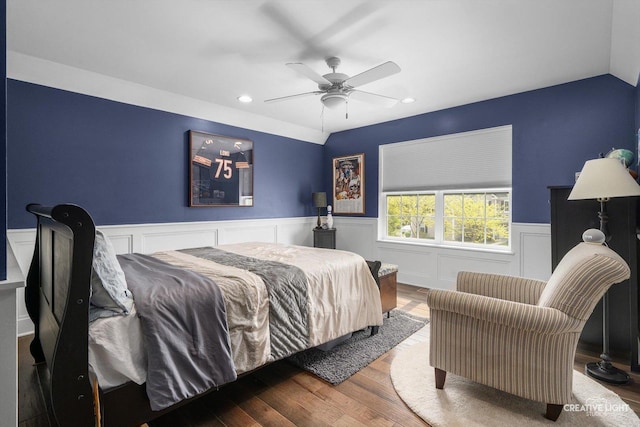 bedroom featuring wood finished floors, recessed lighting, wainscoting, ceiling fan, and a decorative wall