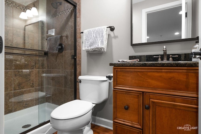 full bathroom featuring a stall shower, toilet, vanity, baseboards, and wood finished floors