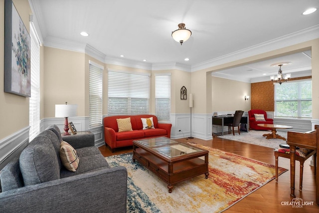 living room featuring wood finished floors, a chandelier, a wainscoted wall, ornamental molding, and recessed lighting