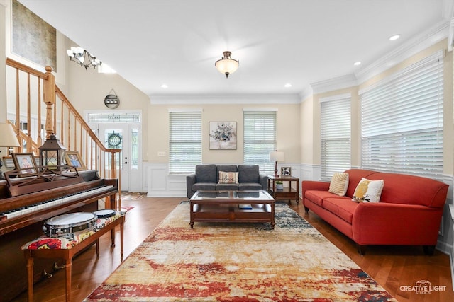living room featuring wood finished floors, crown molding, wainscoting, a decorative wall, and stairway