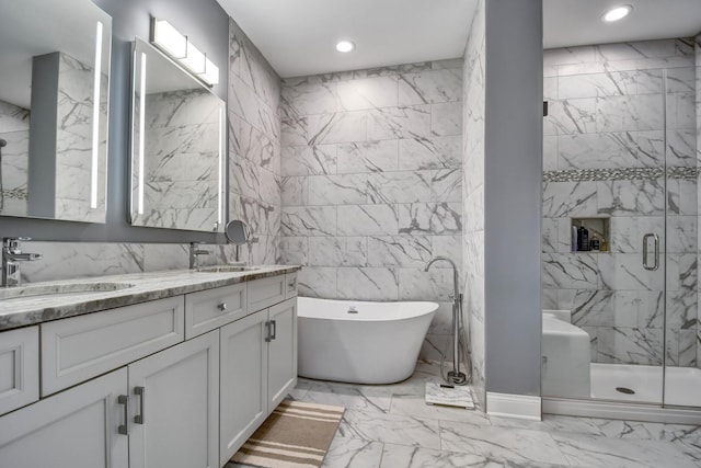 bathroom featuring tile walls, marble finish flooring, a shower stall, a soaking tub, and double vanity