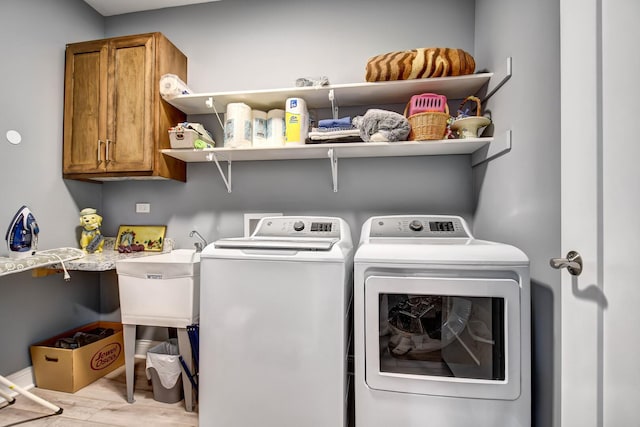 clothes washing area with cabinet space, independent washer and dryer, and wood finished floors
