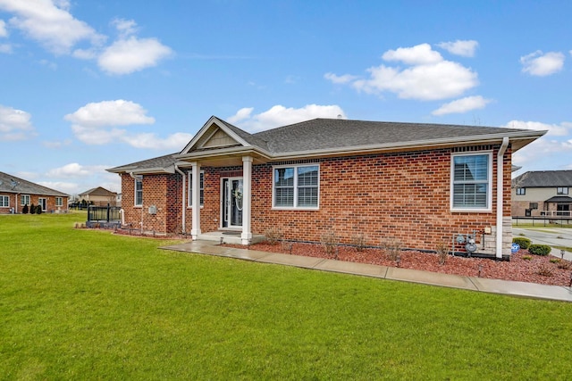 view of front of property with brick siding, a front yard, and roof with shingles