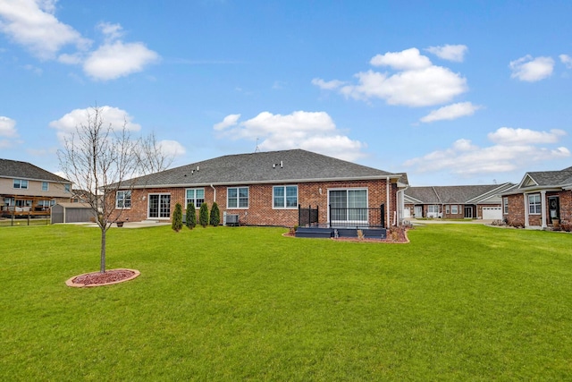 rear view of house featuring brick siding, a yard, central AC, and roof with shingles