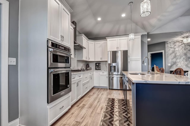 kitchen with stainless steel appliances, a sink, light wood-style flooring, white cabinetry, and light stone counters