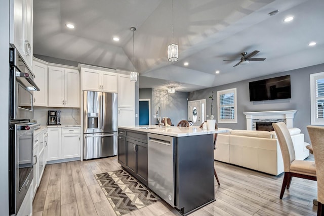 kitchen with stainless steel appliances, open floor plan, light wood finished floors, white cabinets, and ceiling fan