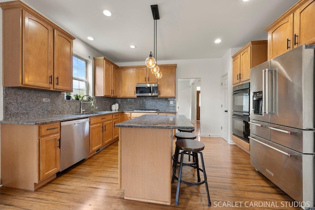 700 Wilmore Dr, Oswego, IL 60543 - kitchen featuring appliances with stainless steel finishes, a sink, a breakfast bar, a center island, and light wood-style flooring