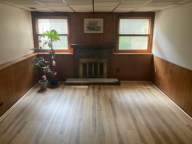 1916 Saginaw Ct, Naperville, IL 60565 - unfurnished living room with a drop ceiling, wainscoting, wood finished floors, a brick fireplace, and wood walls