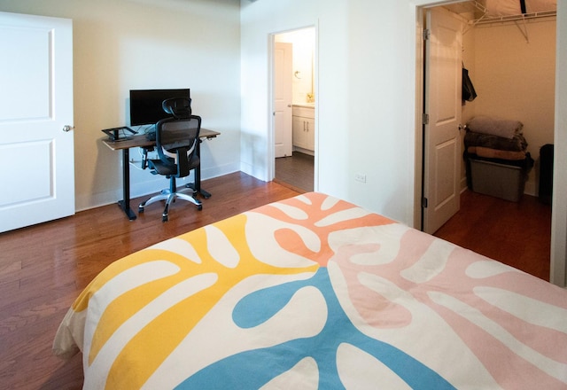 bedroom featuring wood finished floors, a walk in closet, and an office area