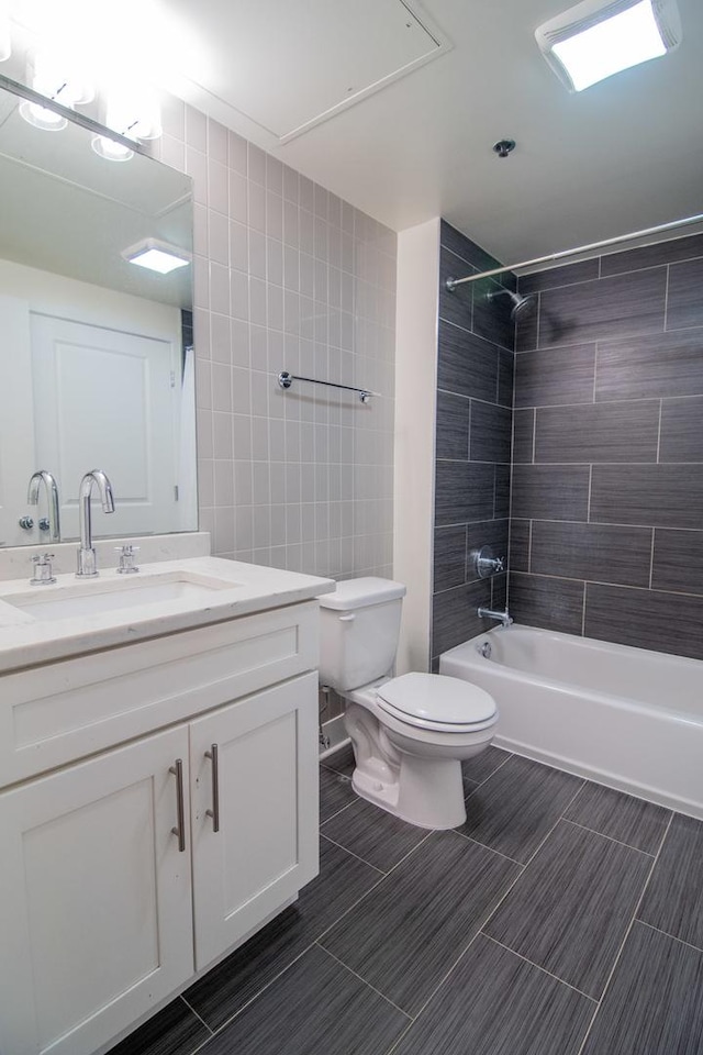 bathroom featuring toilet, vanity,  shower combination, and tile walls