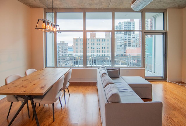 dining space featuring a city view, light wood-style floors, and baseboards